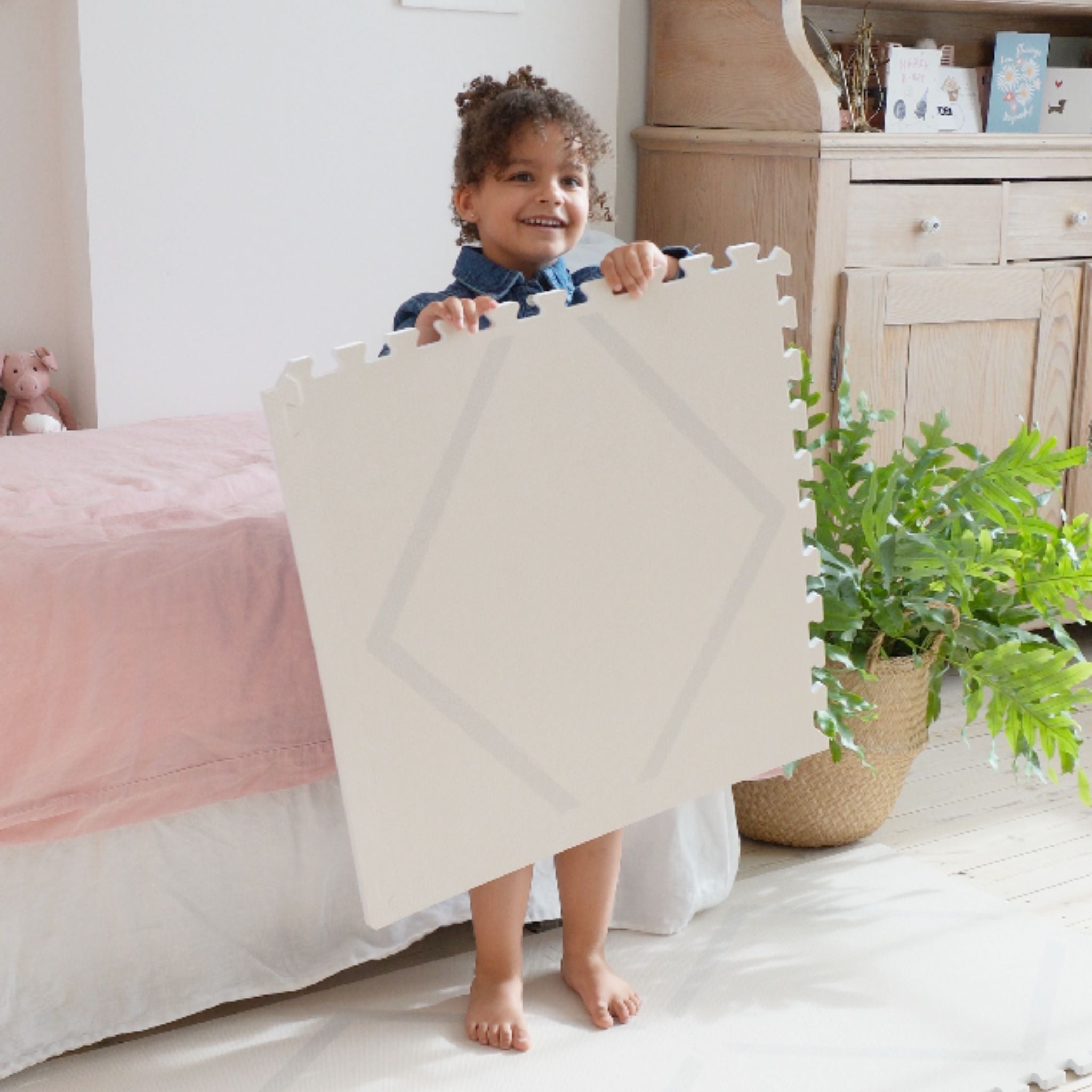 Peuter houdt een tegel van speelmat baby foam Beni Cashmere van Eeveve omhoog, toont het zachte en stevige materiaal