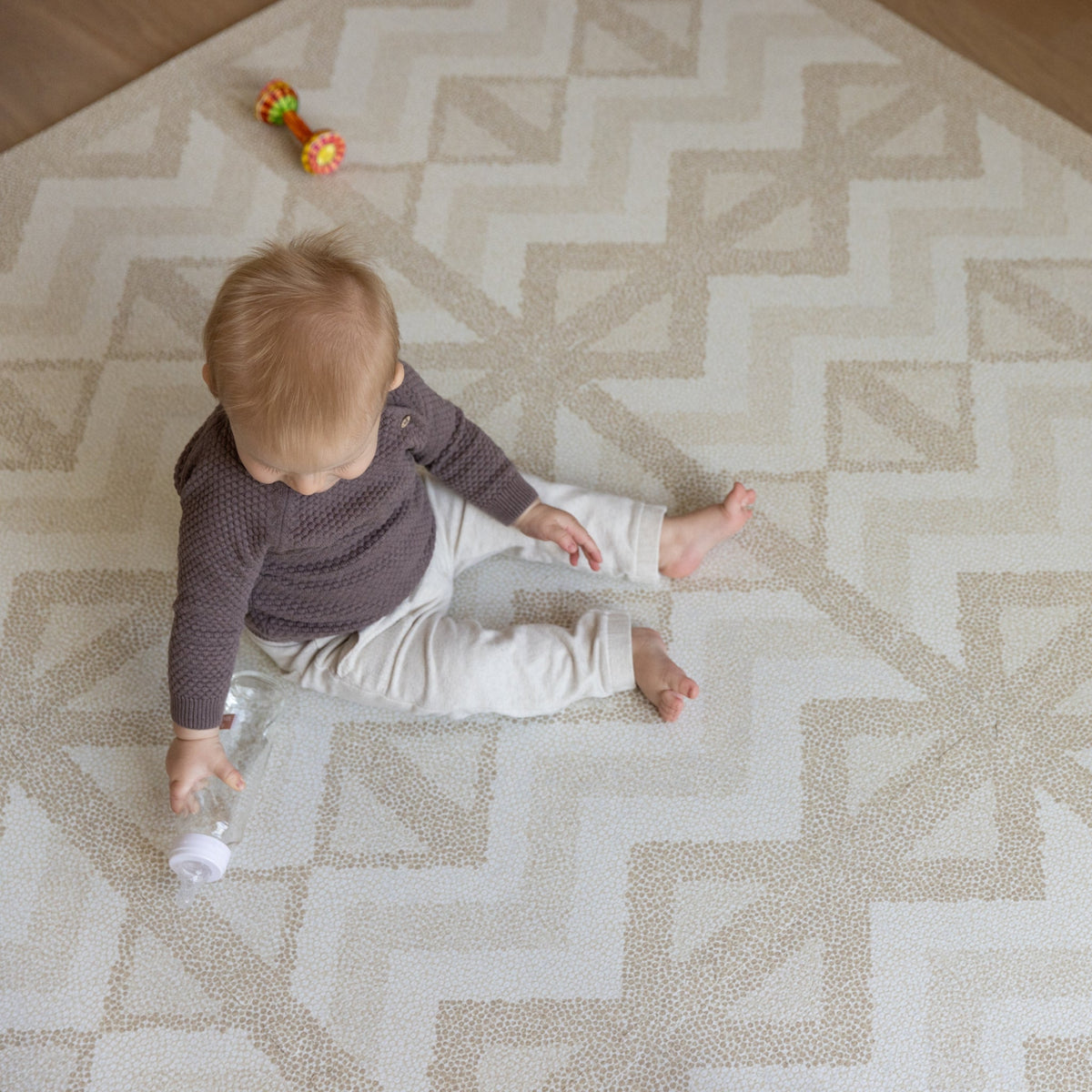 Kilim Sand speelmat met peuter die op de vloer speelt, het puzzelpatroon vult bijna de hele kamer
